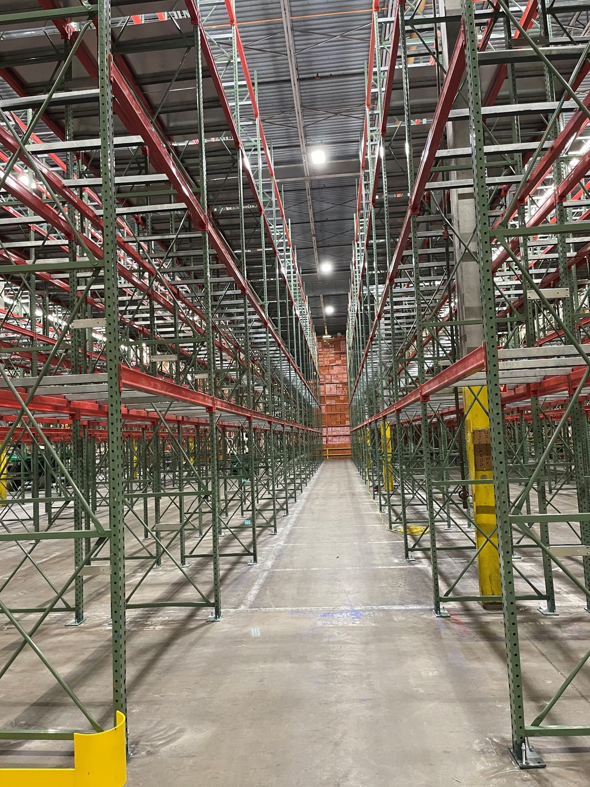 Looking down a very narrow aisle between tall pallet racking runs in a Carrollton, TX document storage building